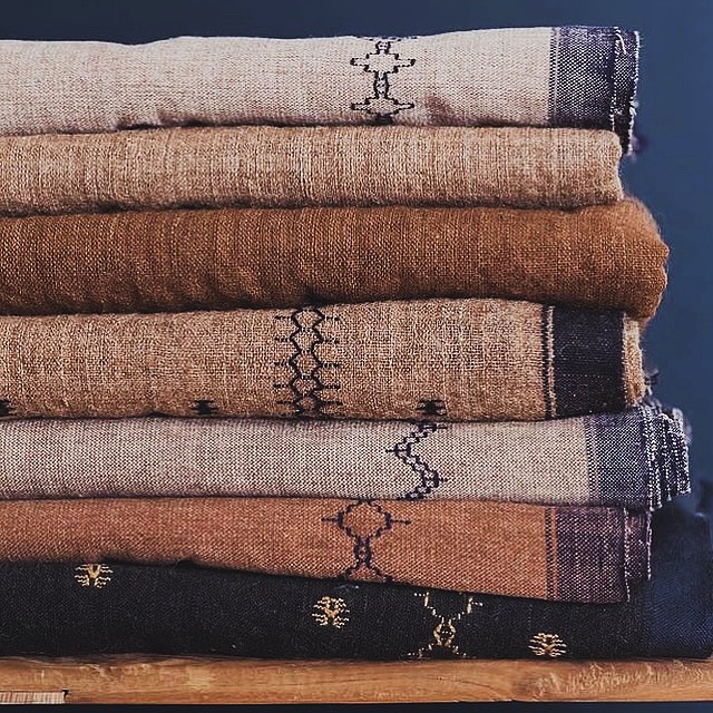 Folded handwoven textiles in warm desert sand hues